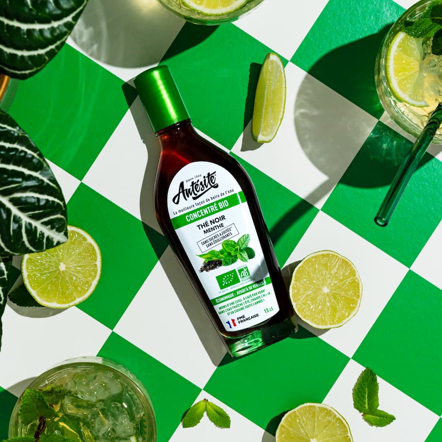 Antésite Thé noir menthe sur une table d'été entouré de citrons verts